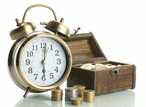 Alarm clock with coins in chest isolated on white
